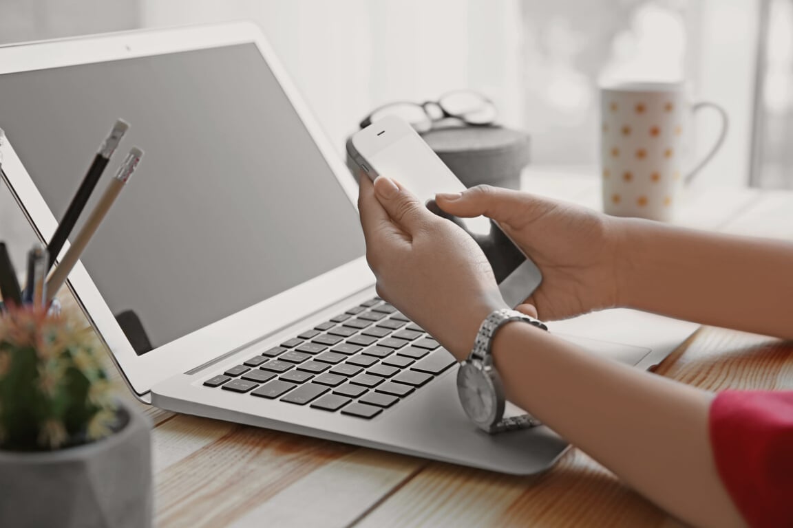 Woman with Cell Phone and Laptop on Wooden Table